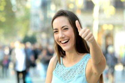 Front view portrait of a happy lady gesturing thumbs up in the street